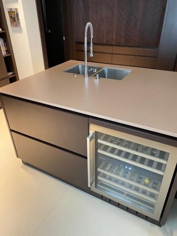 Moderna isola cucina con lavello, rubinetto alto e cantinetta per vini integrata con sportello in vetro.