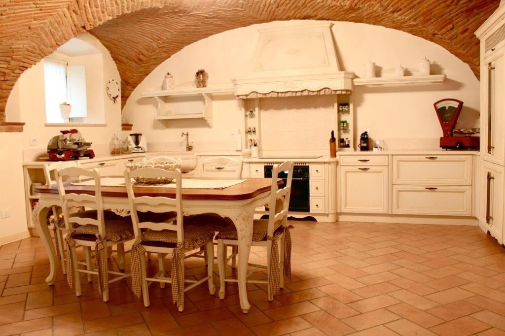 Cucina rustica con tavolo da pranzo in legno e mobili bianchi.