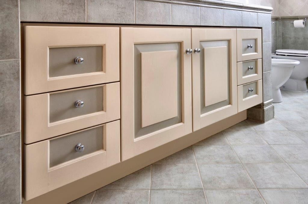 Mobile da bagno beige con tre cassetti, ante e piano lavabo.