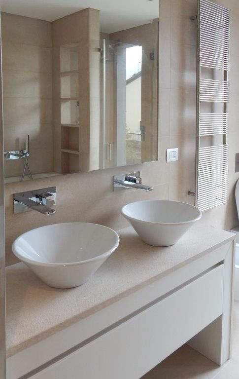 Mobile bagno moderno con due lavabi a ciotola bianchi e un grande specchio e dettagli in legno.