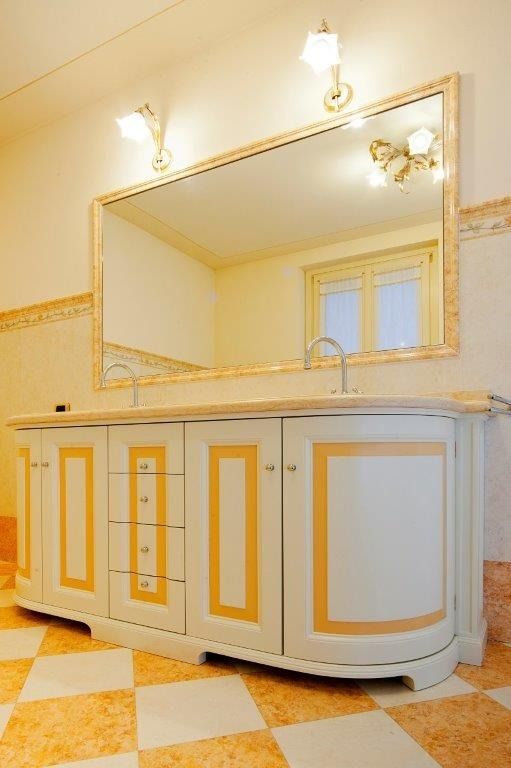 Elegante mobile da bagno bianco e oro con ampio specchio e pavimento piastrellato a scacchiera.