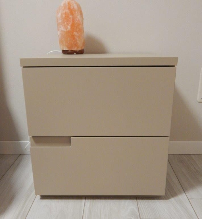 Mobiletto beige a due cassetti addossato alla parete.