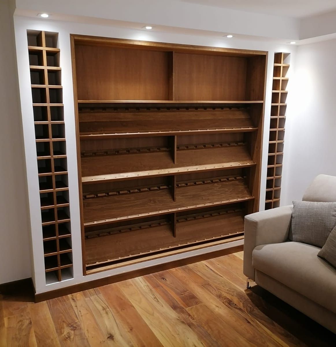 Parete attrezzata con scaffalature in legno e faretti.