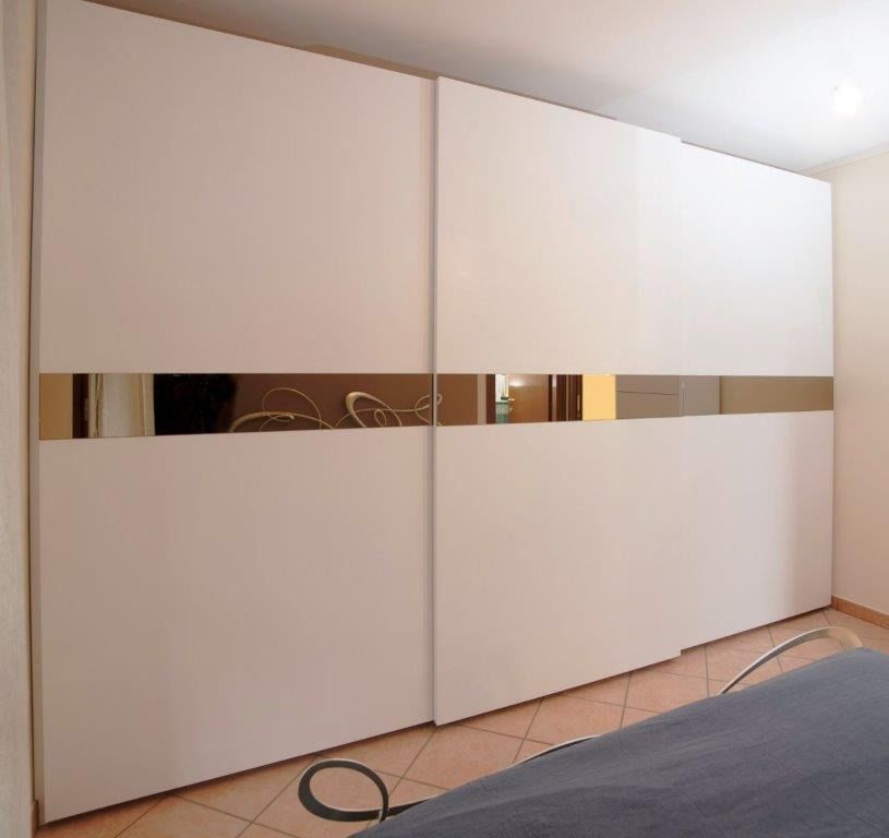 Armadio scorrevole bianco con fascia centrale a specchio in una camera da letto.