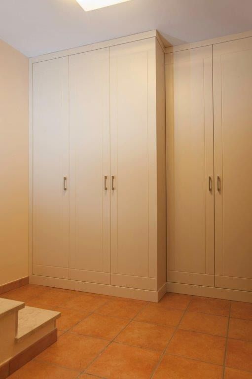 Armadi a muro bianchi lungo una parete beige.