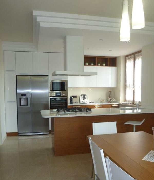 Cucina moderna con elettrodomestici in acciaio inossidabile, mobili bianchi, isola in legno e tavolo da pranzo