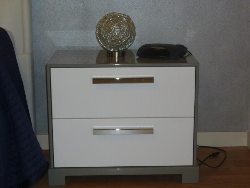 Comodino bianco a due cassetti con maniglie argentate.