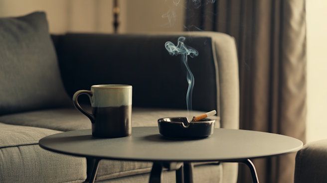 Coffee mug and ashtray on a small coffee table in OKC with a cigarette burning out