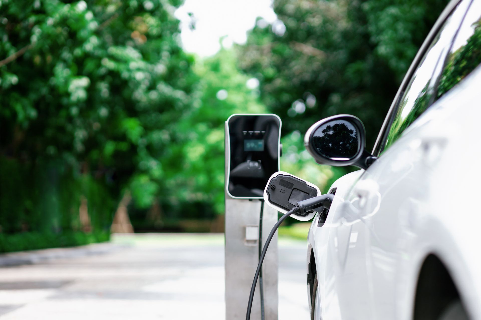 Close-up of an EV charging station installed at a home, charging a white car.]