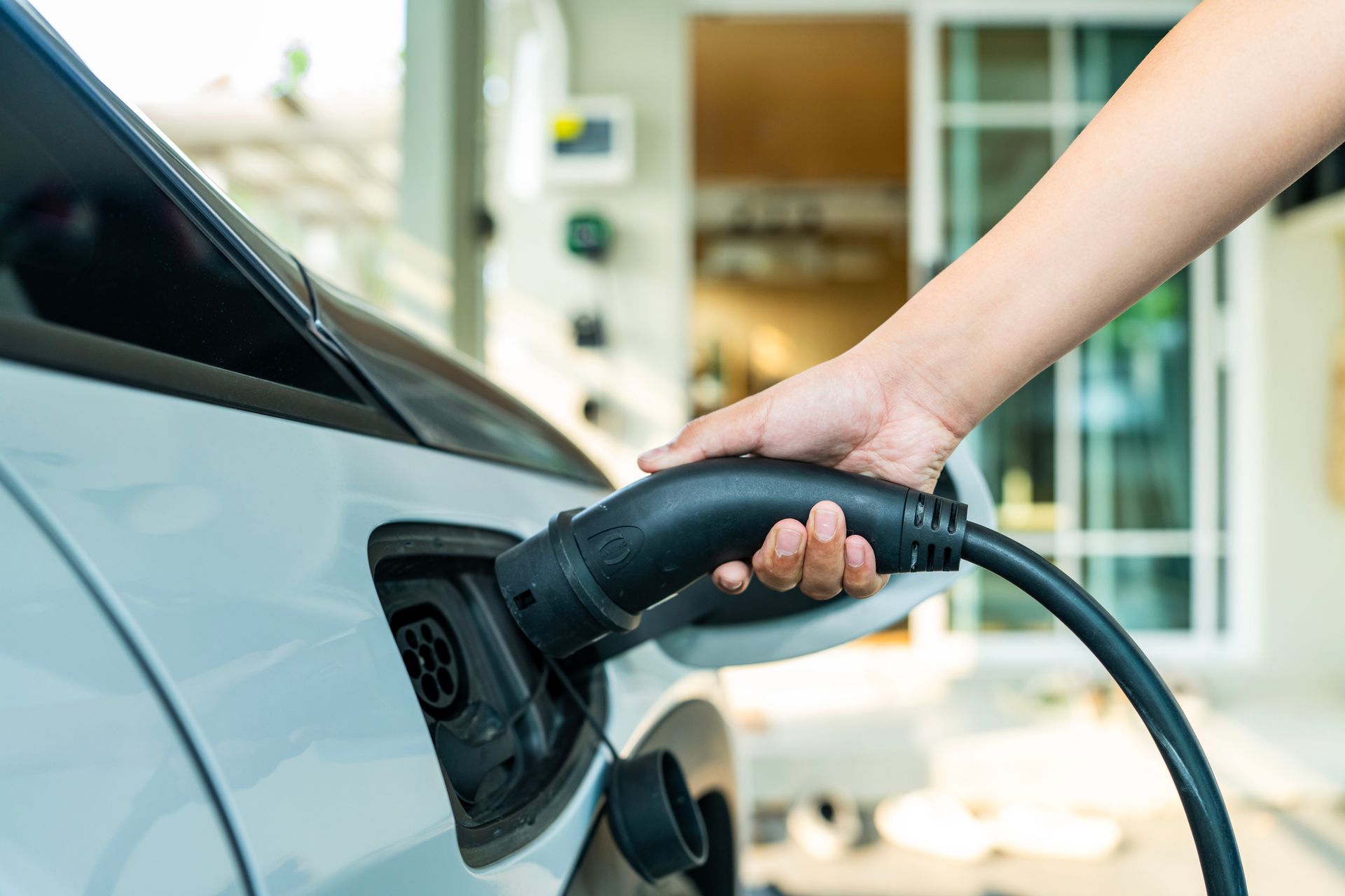 A person connects an electric car to a charging point.