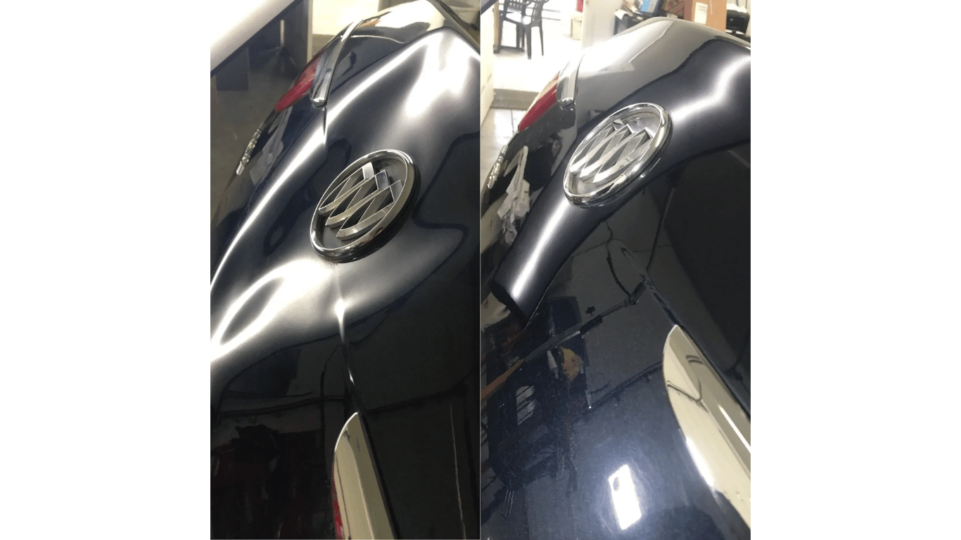 A black car with a logo on the hood is sitting in a garage.