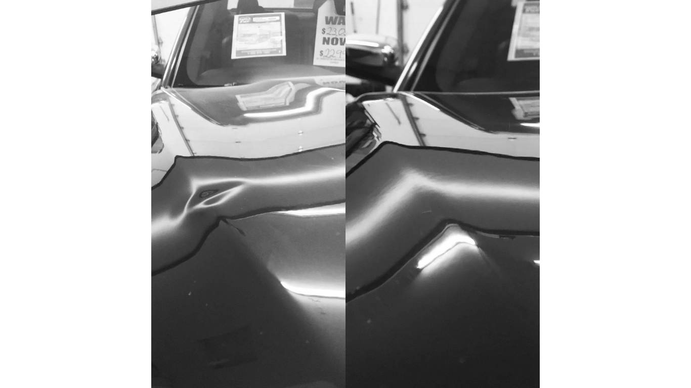 A black and white photo of a car with a dent in the hood.