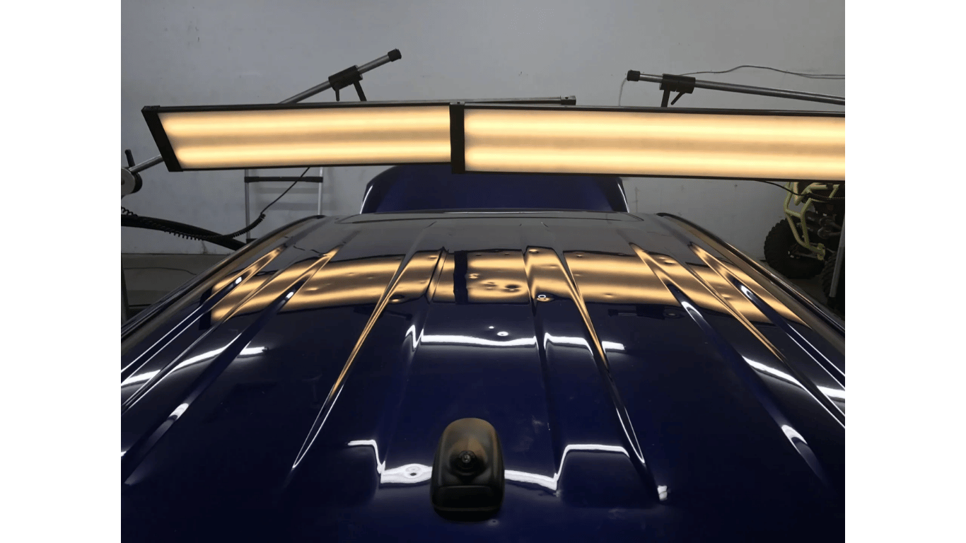 The roof of a blue car is being repaired with lights.