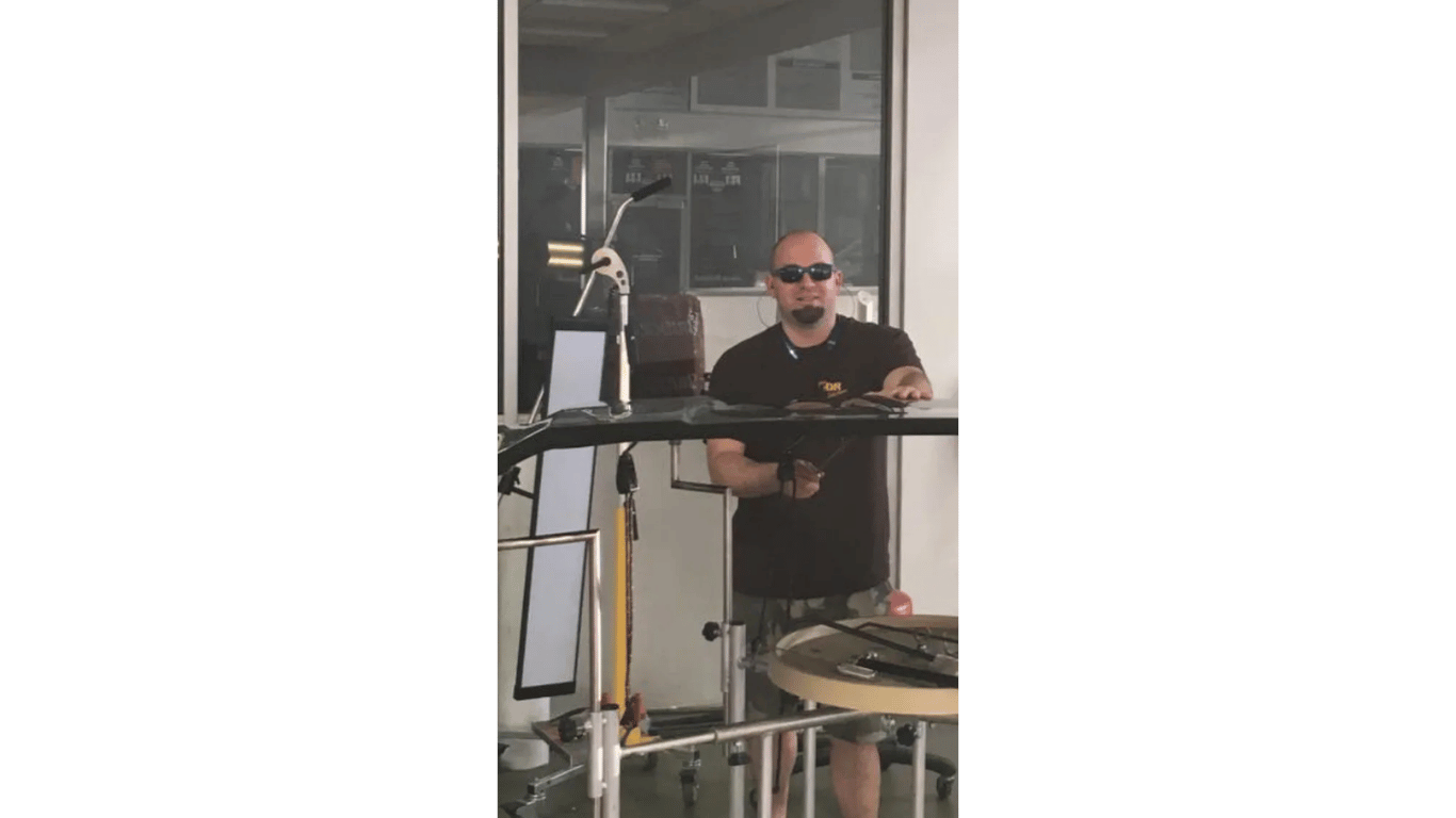 A man in sunglasses is standing in front of a window.