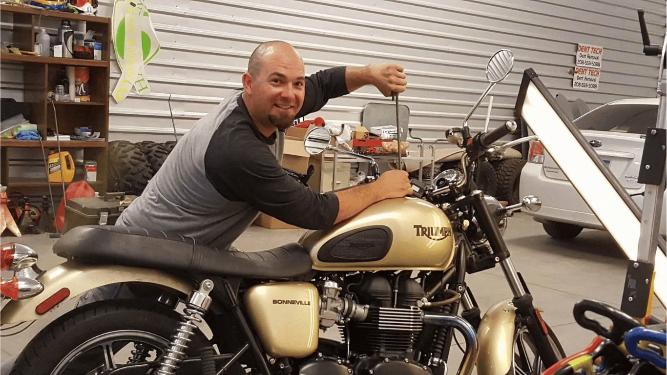 A man is sitting on a motorcycle in a garage.