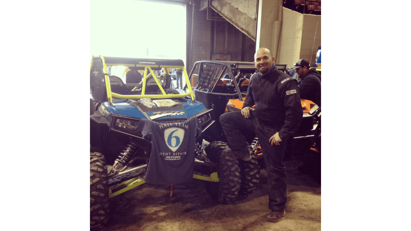 A man is standing next to a atv in a garage.