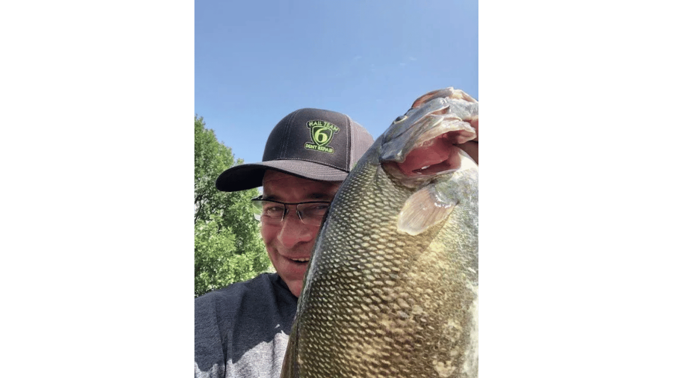 A man is holding a large fish in his hands.