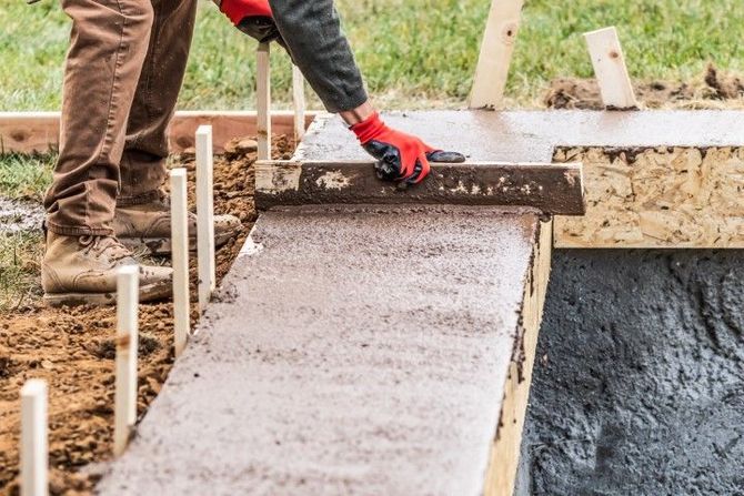 A man is spreading concrete on a sidewalk.