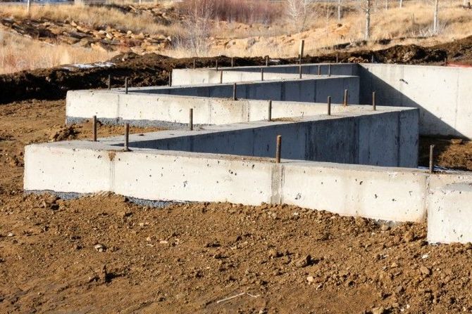 A concrete foundation is being built in a dirt field