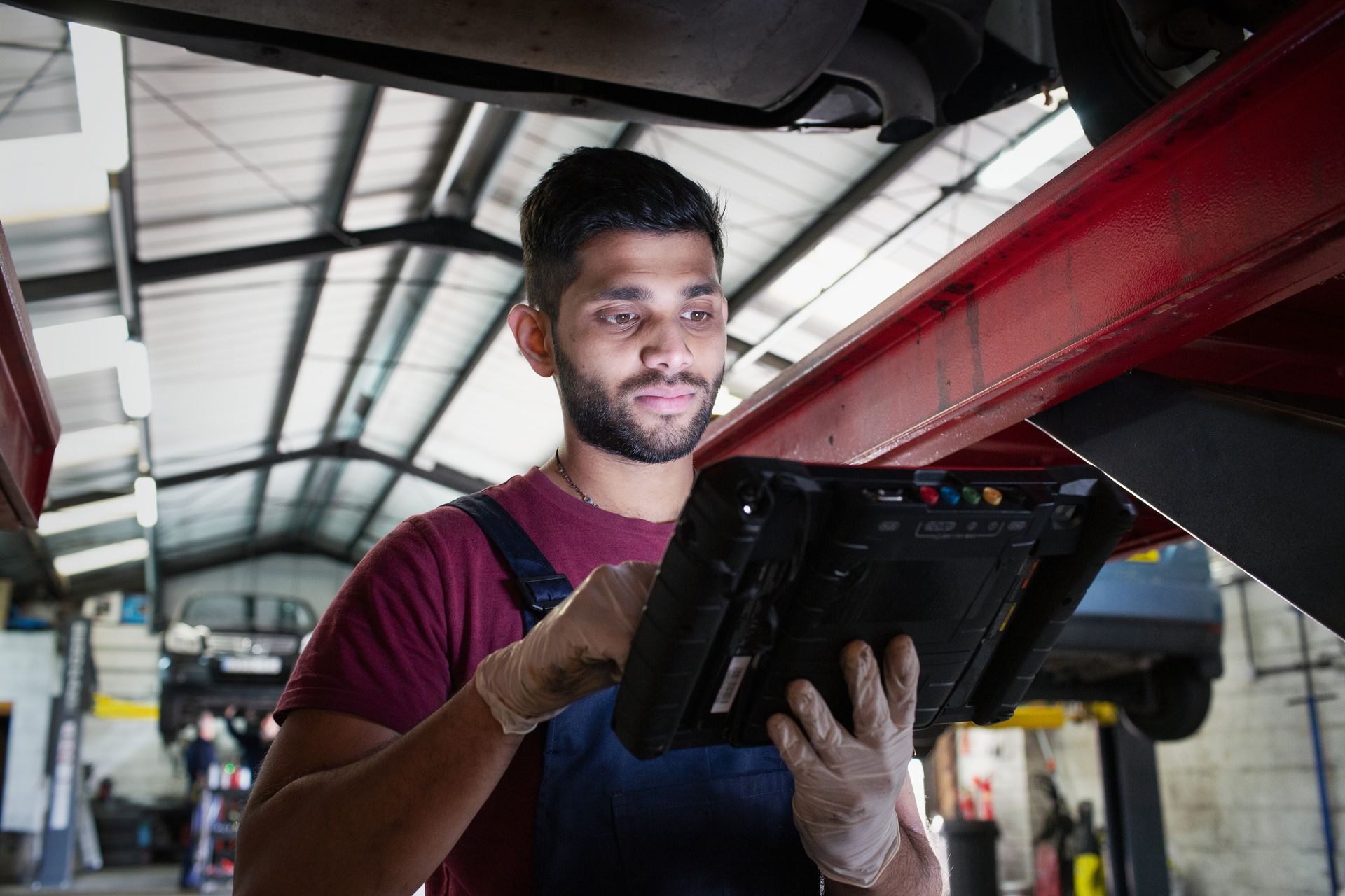Focused mechanic using diagnostic equipment in an auto repair shop.