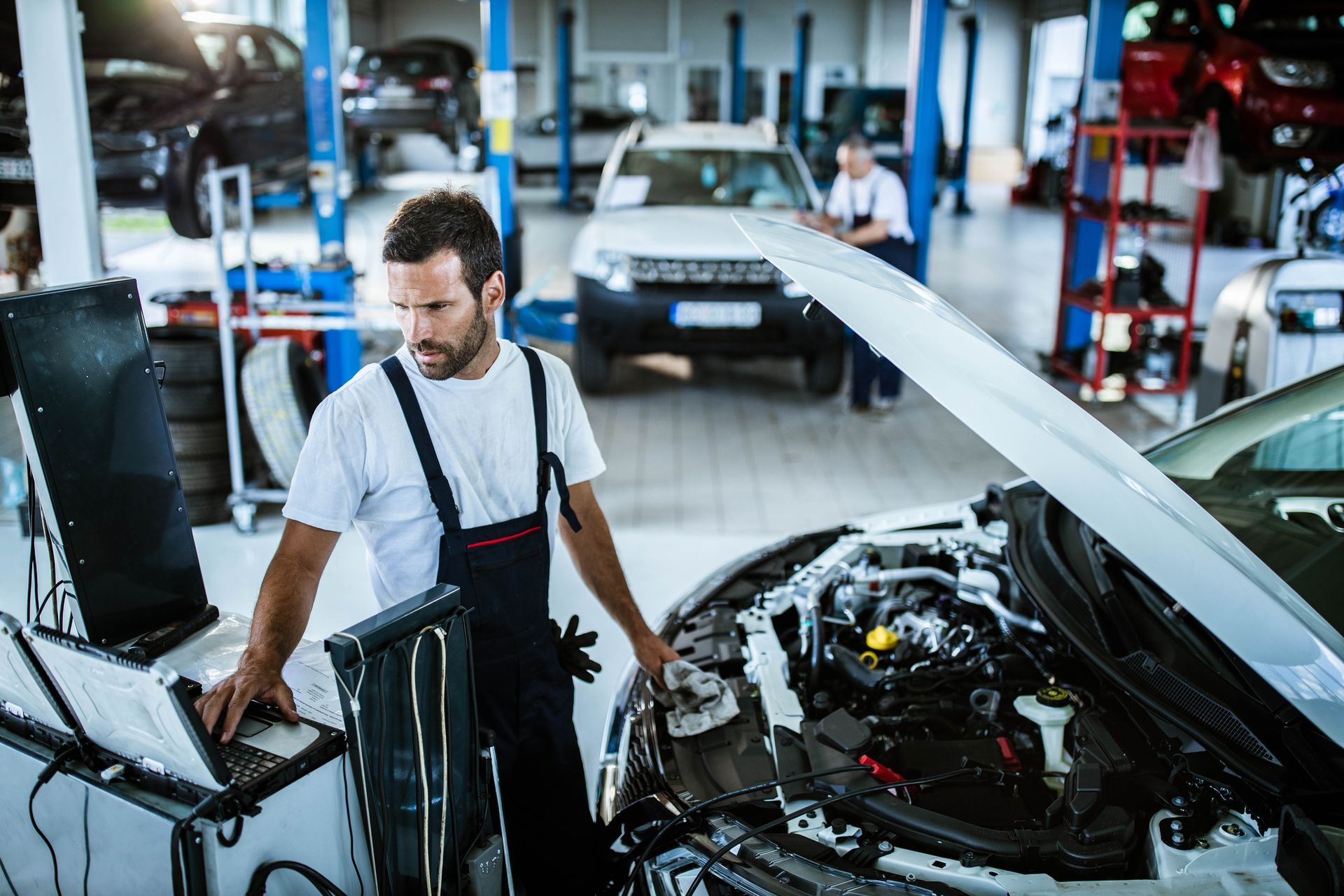 Car technician using diagnostic tools in repair shop for precise automotive diagnostic services.
