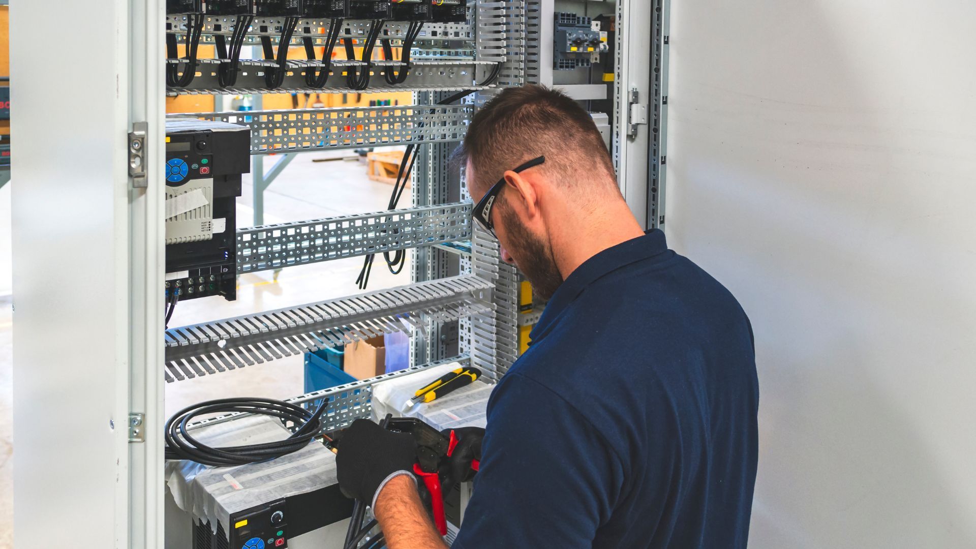 A man is working on a electrical box in a factory.