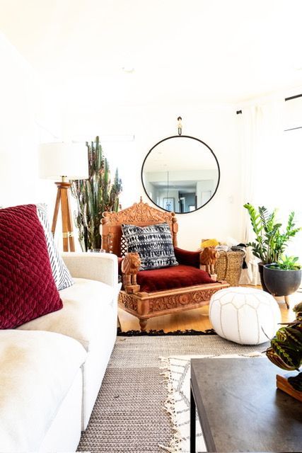 A living room with a couch , chair , coffee table and mirror.