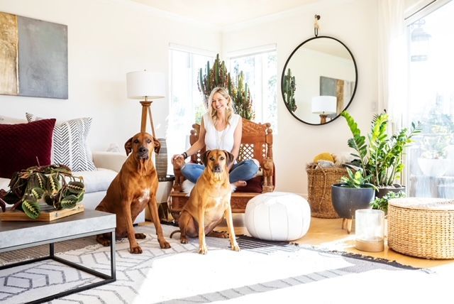 A woman is sitting in a chair with two dogs in a living room.