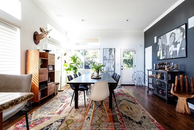 A dining room with a long table and chairs and a rug.