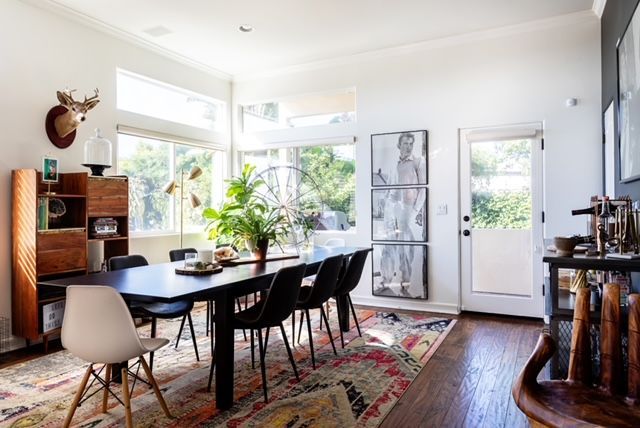 A dining room with a long table and chairs and a deer head on the wall.