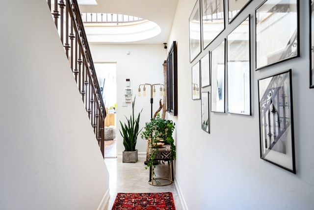 A hallway with a staircase and pictures on the wall.