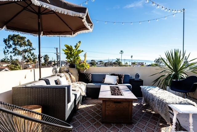 A patio with a couch , chairs , coffee table and umbrella.