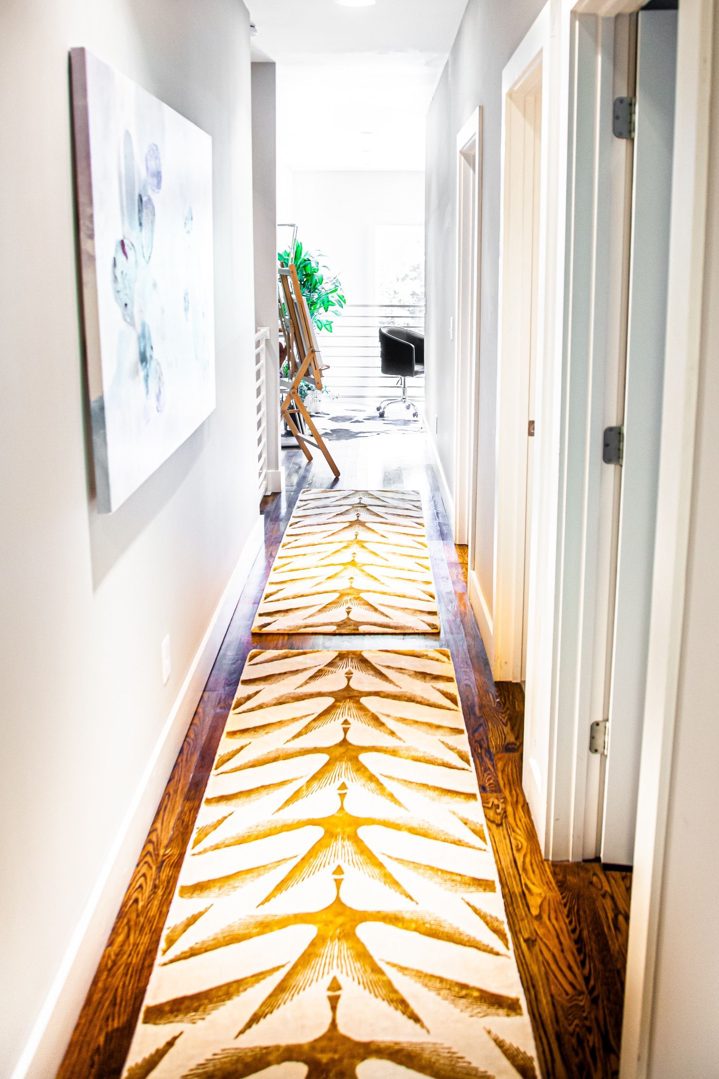 A long hallway with a rug on the floor and a painting on the wall.