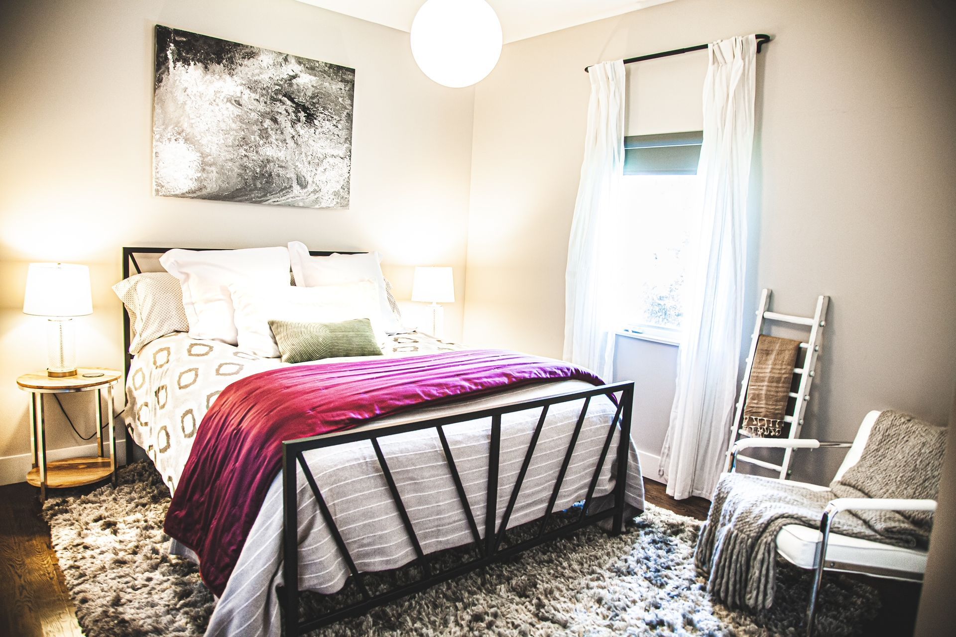 A bedroom with a bed , chair , rug and painting on the wall.