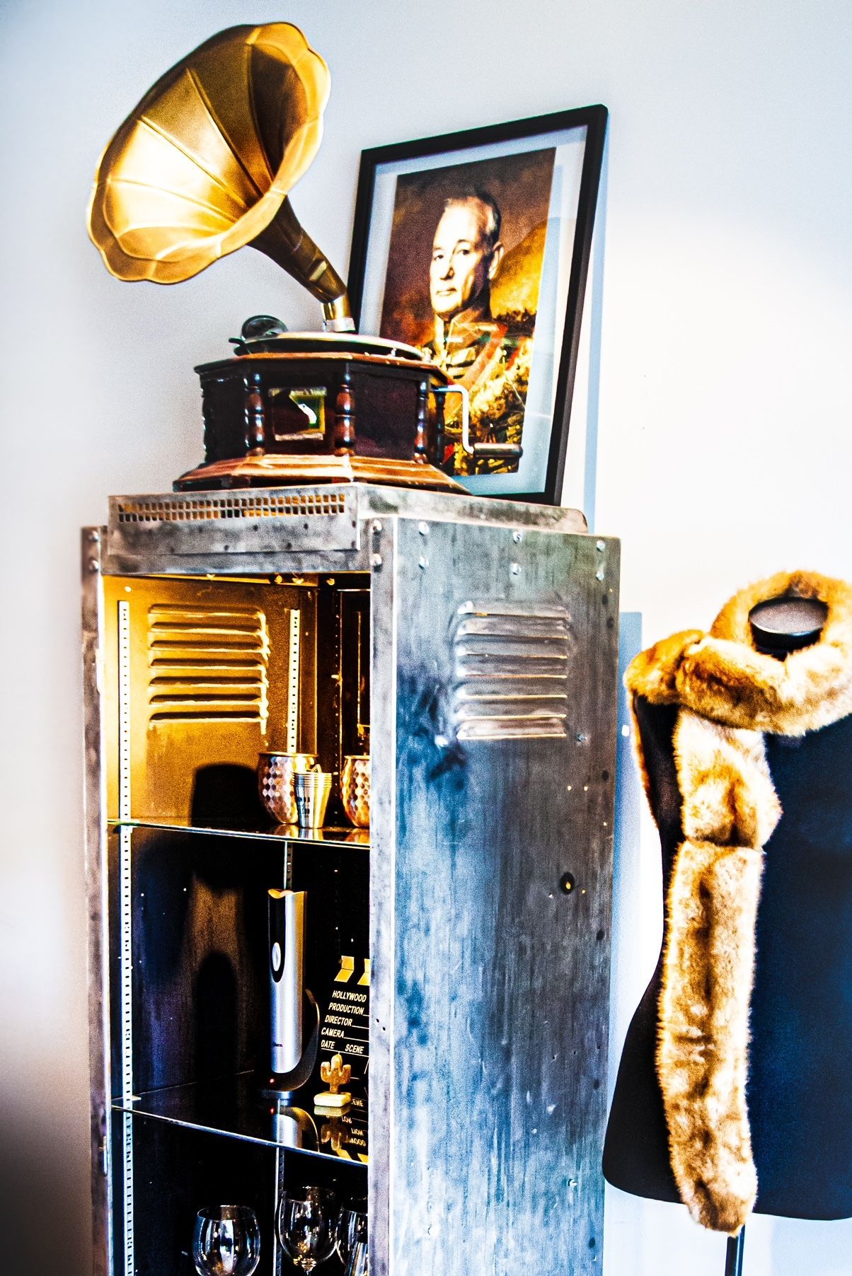 A record player is sitting on top of a wooden cabinet next to a mannequin.