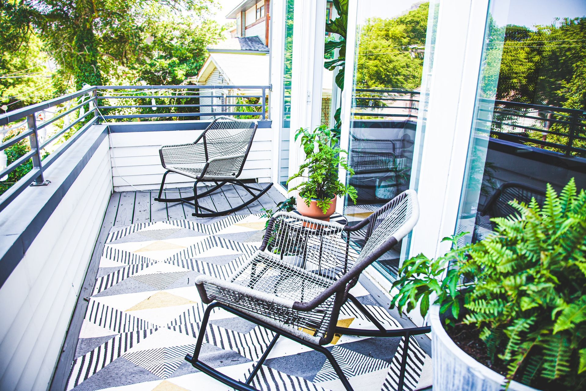 There are two rocking chairs on the porch of a house.