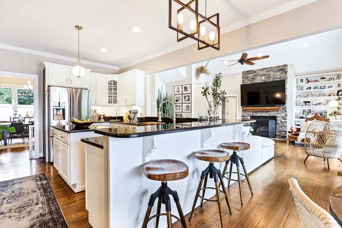 A kitchen with a large island and stools in a house.
