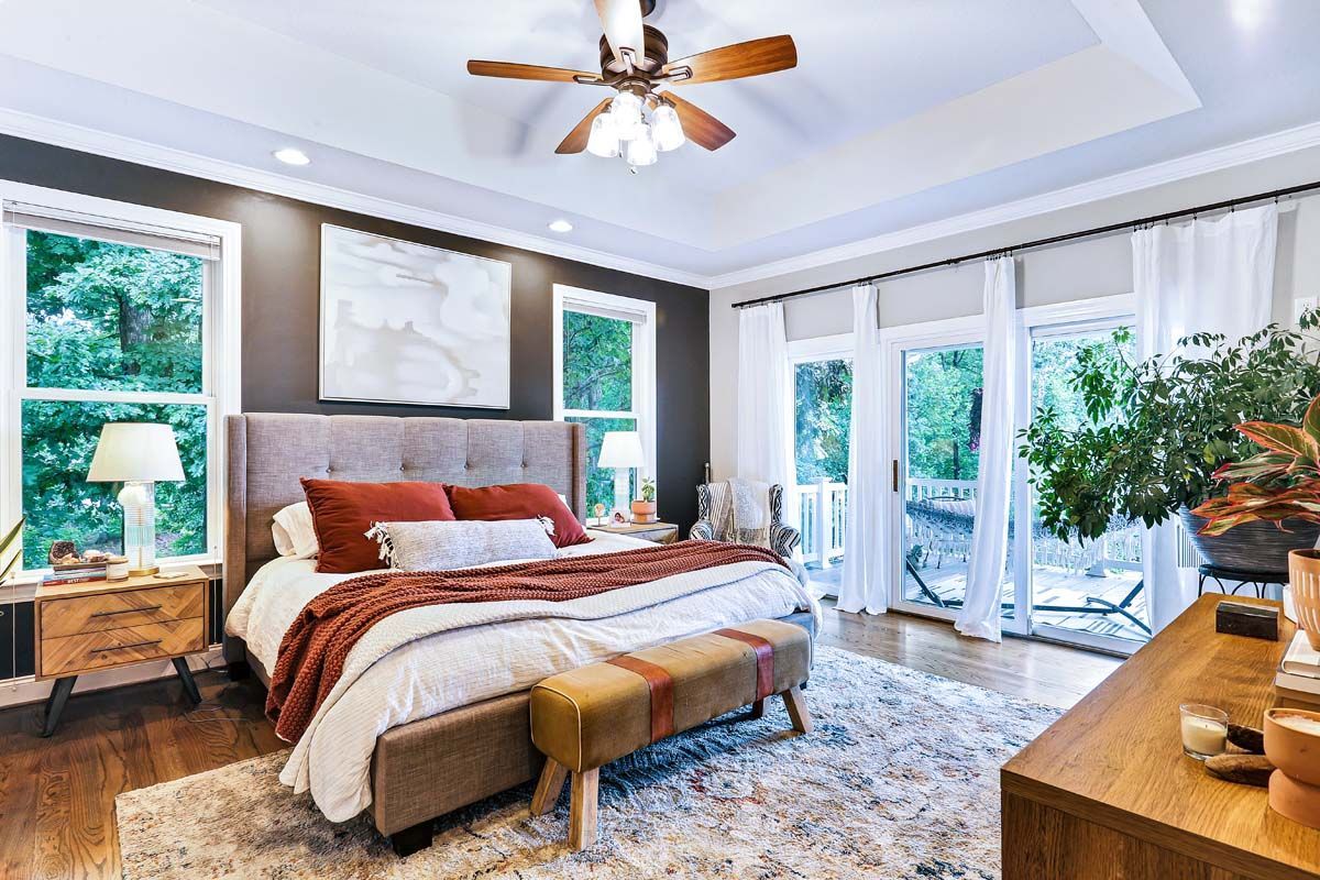 A bedroom with a ceiling fan and a large bed.
