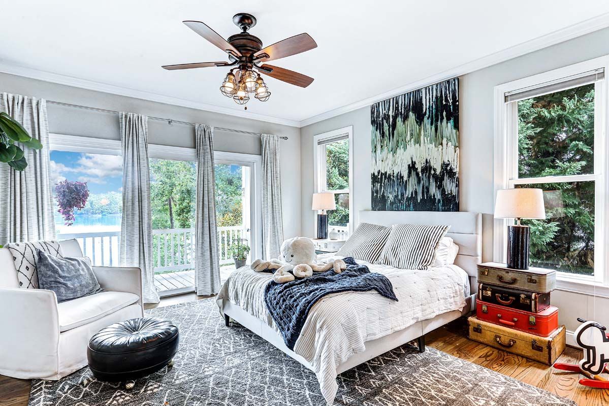 There is a ceiling fan in the bedroom with a large bed.