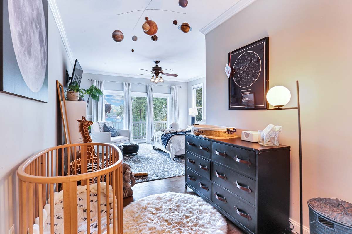 A baby 's room with a crib , dresser , and lamp.