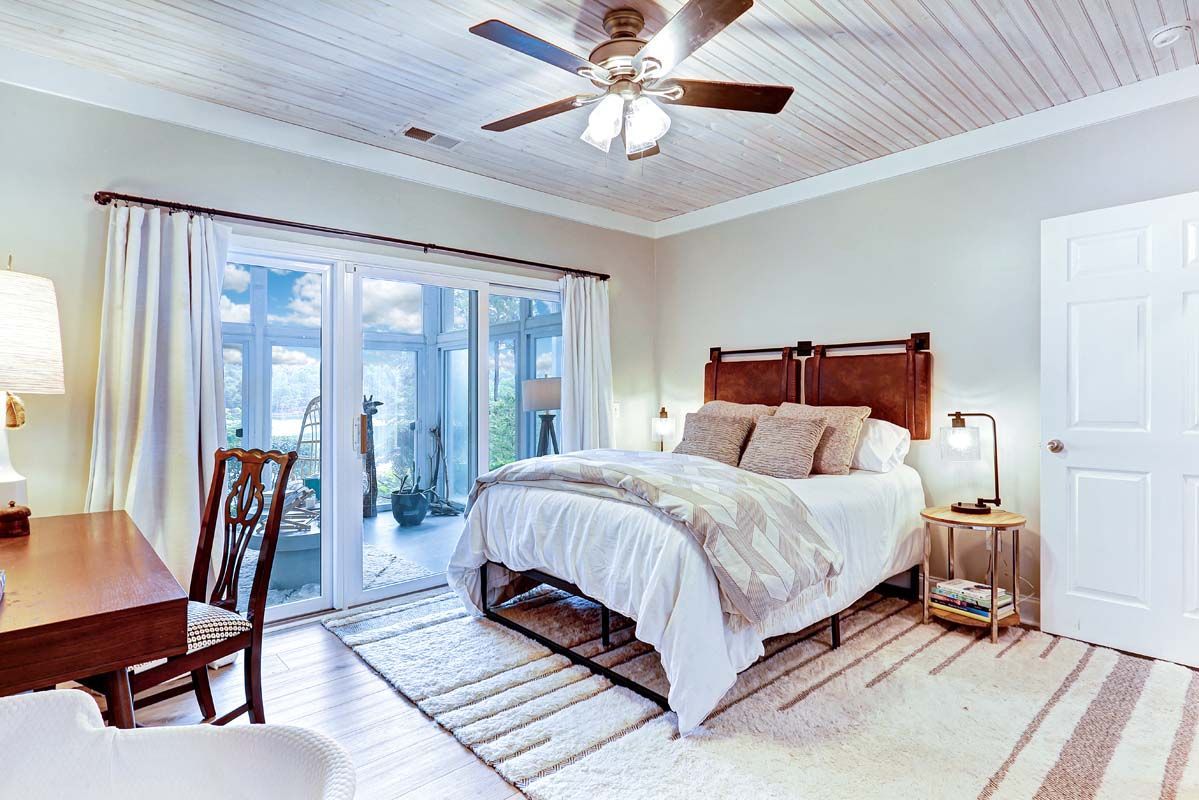 A bedroom with a bed , desk , chair and ceiling fan.