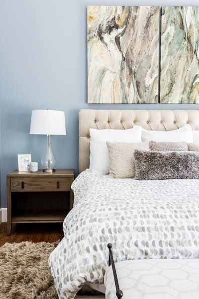 A bedroom with a bed , nightstand , lamp and painting on the wall.