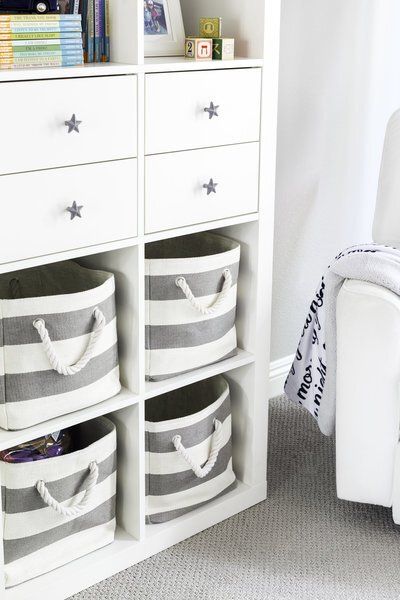 A white shelf with gray and white striped baskets on it