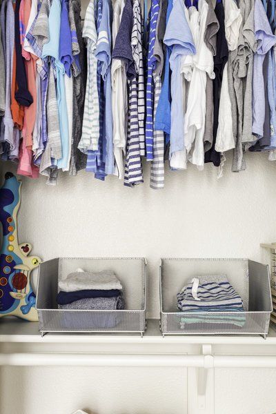 A closet filled with lots of clothes and two baskets.