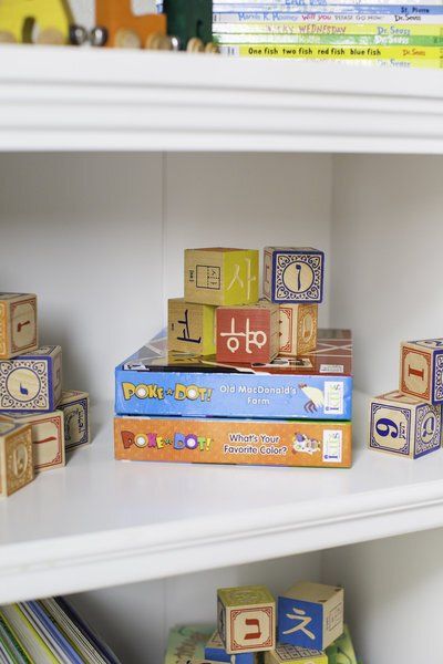 A stack of books and blocks on a white shelf