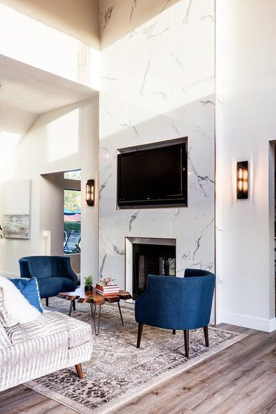 A living room with a fireplace , chairs , and a flat screen tv.