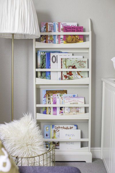 A white bookshelf filled with books and magazines in a room.