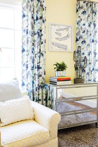 A living room with a chair , table , and curtains.