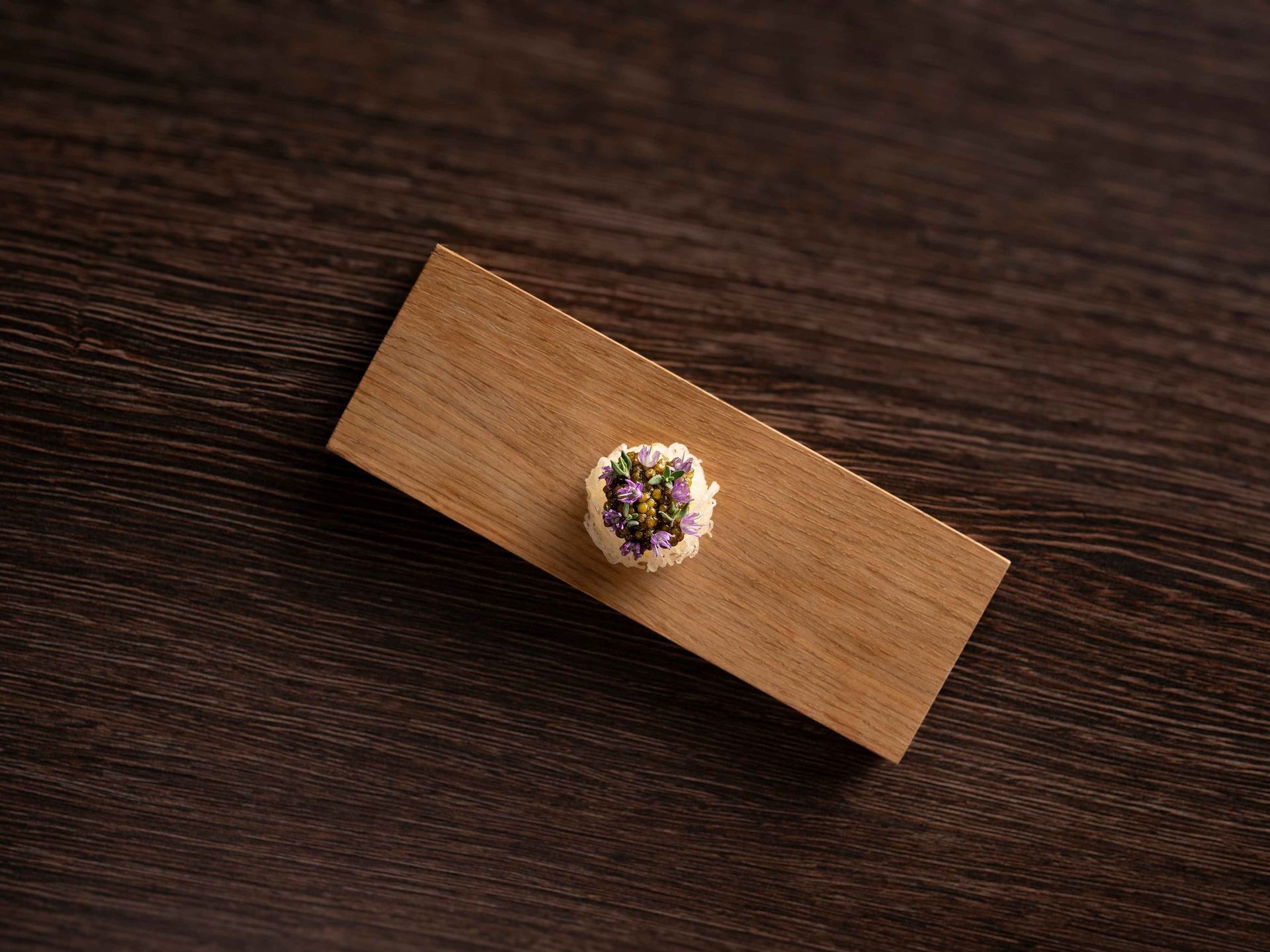 A small piece of wood with a flower on it is sitting on a wooden table.