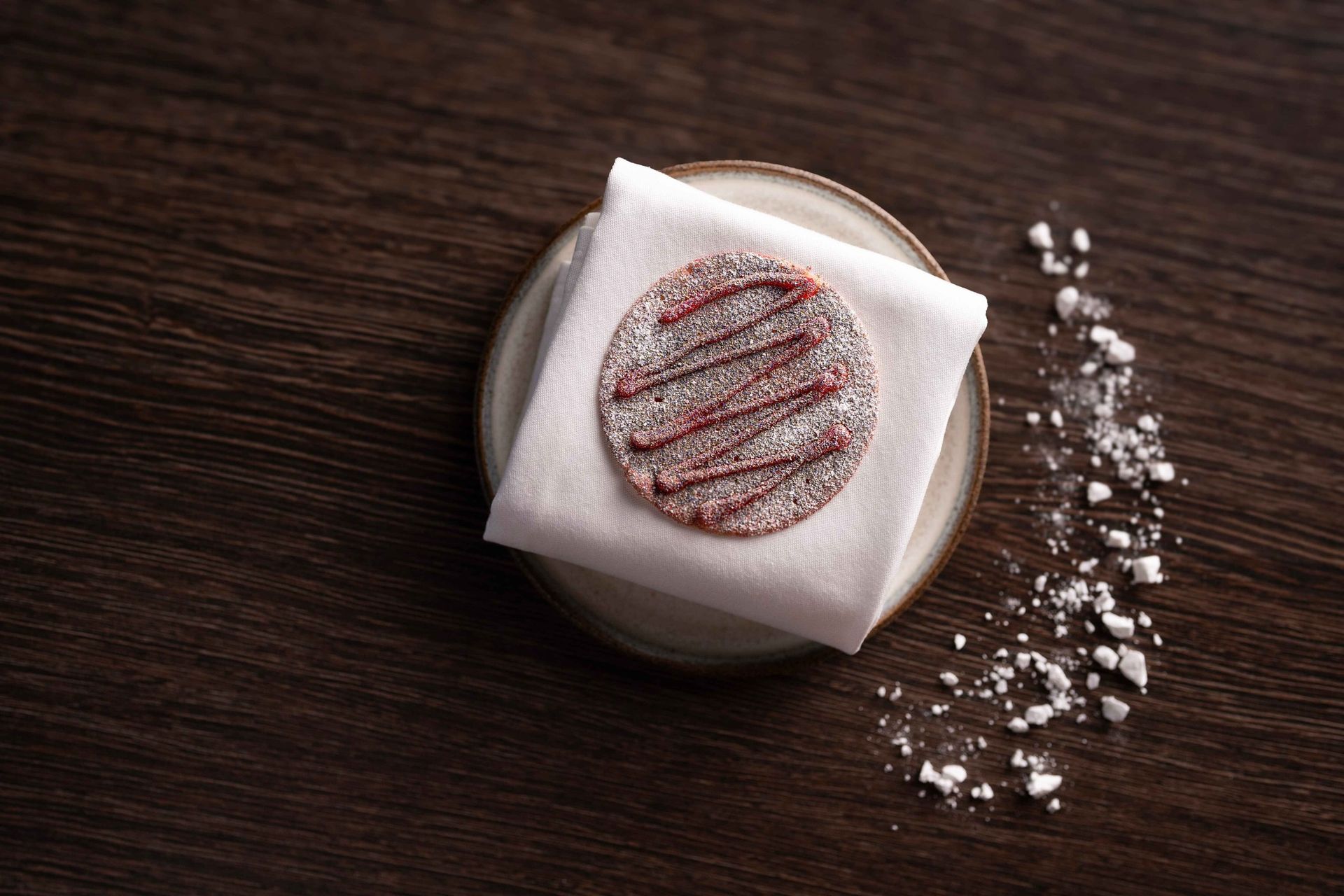 A cookie on a napkin on a plate on a wooden table.
